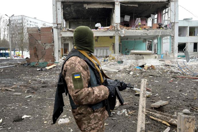 Un soldado ucraniano, frente a edificios destruidos.