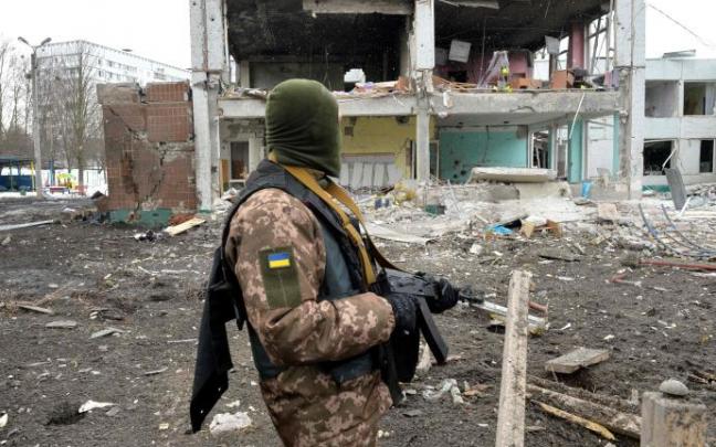 Un soldado ucraniano, frente a edificios destruidos.