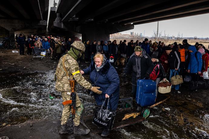 Un soldado ucraniano, junto a decenas de refugiados.