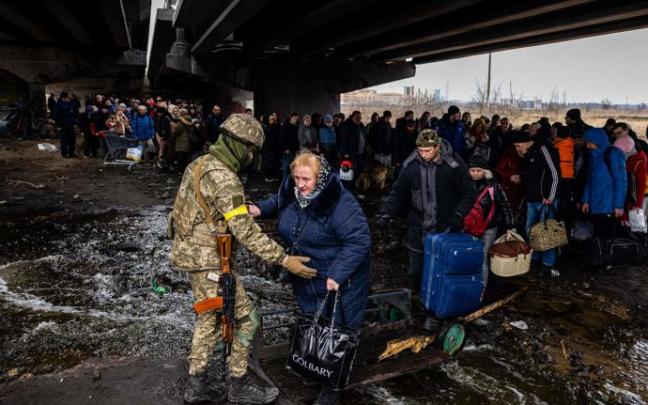 Un soldado ucraniano, junto a decenas de refugiados.