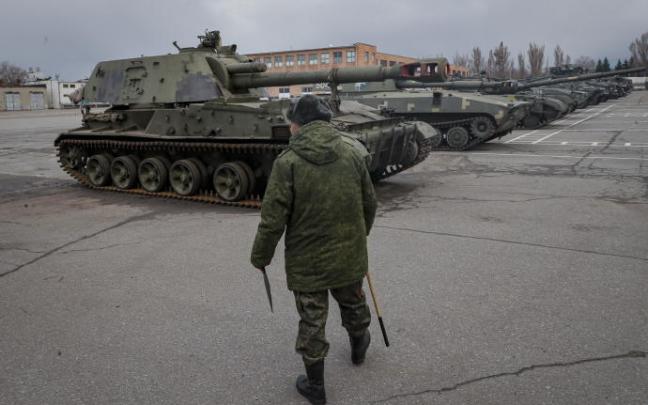 Un militar camina frente a tanques ucranianos abandonados.