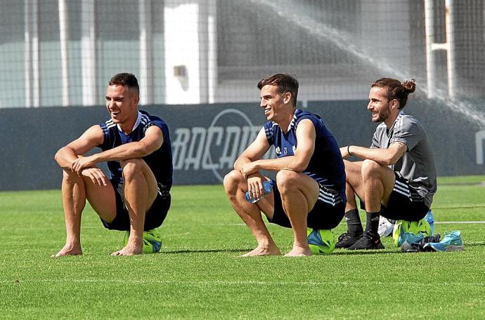 Unai García e Iñigo Pérez, descalzos, observan el entrenamiento de sus compañeros junto a Pablo Iriarte, uno de los preparadores físicos.