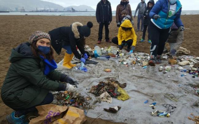 Un grupo de voluntarios retira basuras de la playa de Ereaga, en Getxo.