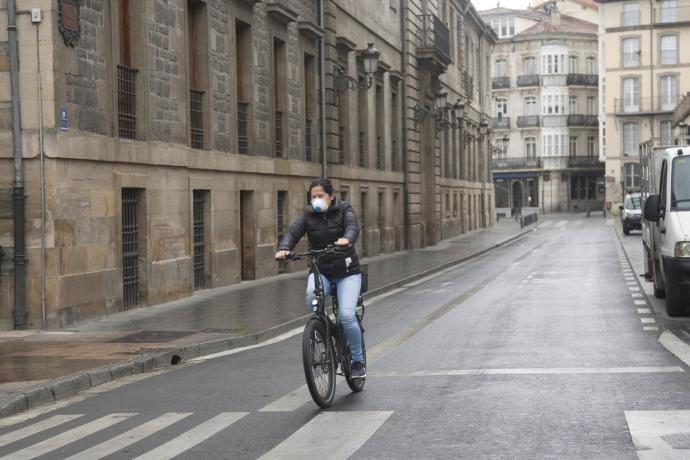 Una persona andando en bici con mascarilla.