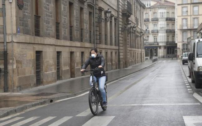 Una persona andando en bici con mascarilla.