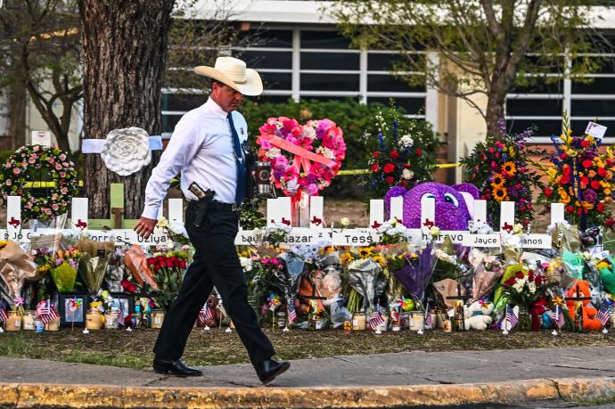 Un policía camina frente al memorial en homenaje a las víctimas en Uvalde.