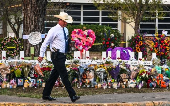 Un policía camina frente al memorial en homenaje a las víctimas en Uvalde.