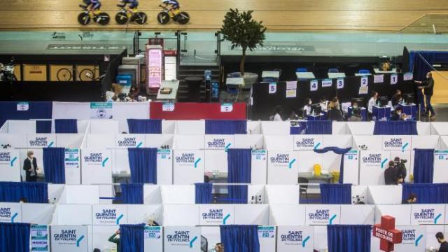 Vacunación en el velódromo francés de Saint-Quentin-en-Yvelines, con los corredores entrenando mientras los sanitarios administran las dosis.