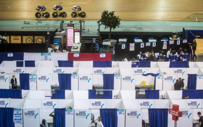 Vacunación en el velódromo francés de Saint-Quentin-en-Yvelines, con los corredores entrenando mientras los sanitarios administran las dosis.