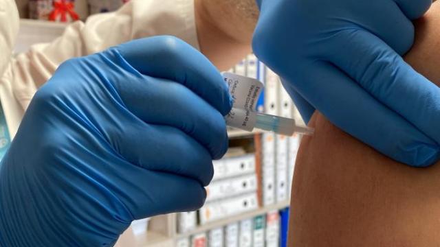 Una sanitaria administra una vacuna a un paciente.