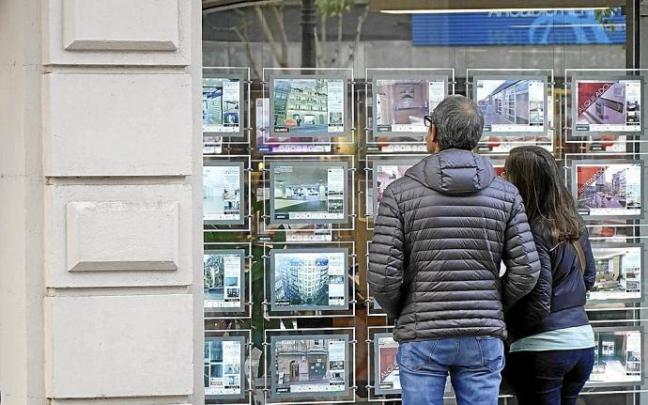 Una pareja observa precios de pisos en el escaparate de una inmobiliaria. Foto: P. Viñas