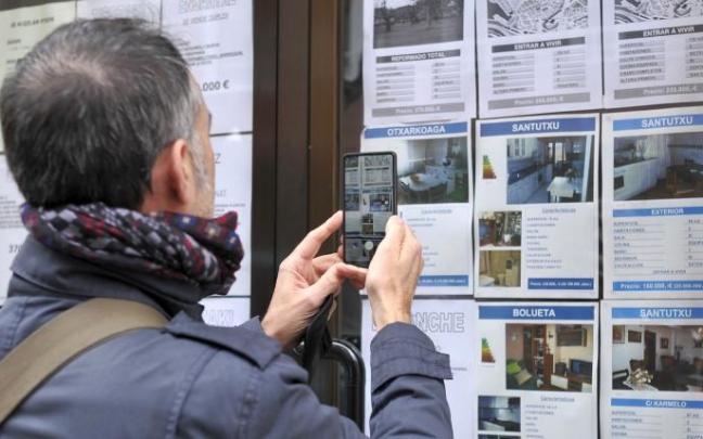 Un comprador mira el escaparate de una inmobiliaria.