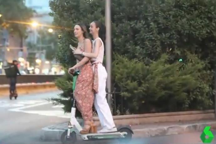 Victoria Federica (detrás), compartiendo patinete con una amiga por Madrid sin casco y utilizando el teléfono móvil.