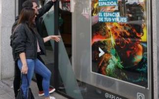 Una pareja consulta el escaparate de una agencia de Eroski Bidaiak.