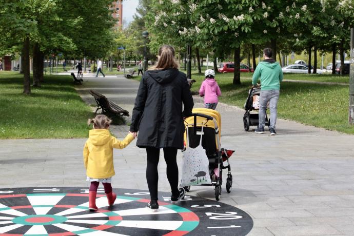 Varias familias pasean por un parque de Vitoria.