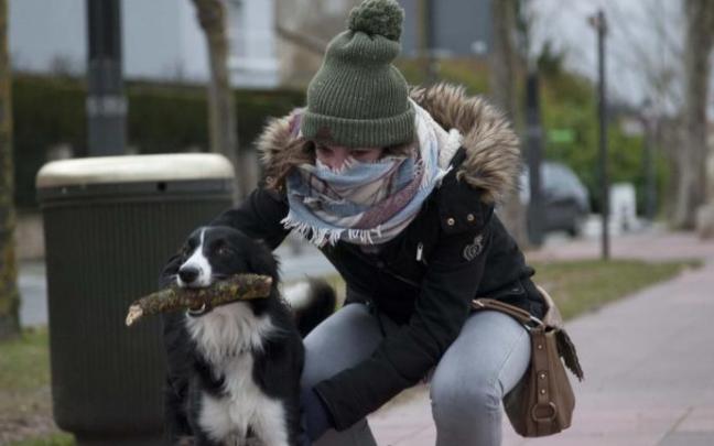Una joven se abriga para protegerse del frío junto a su perro