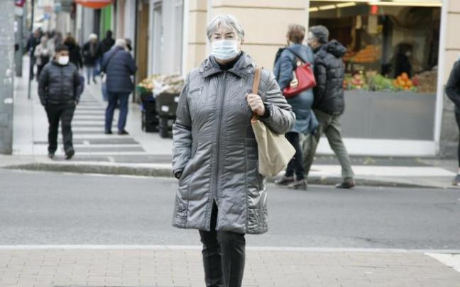 Una mujer protegida con su mascarilla pasea por Vitoria.