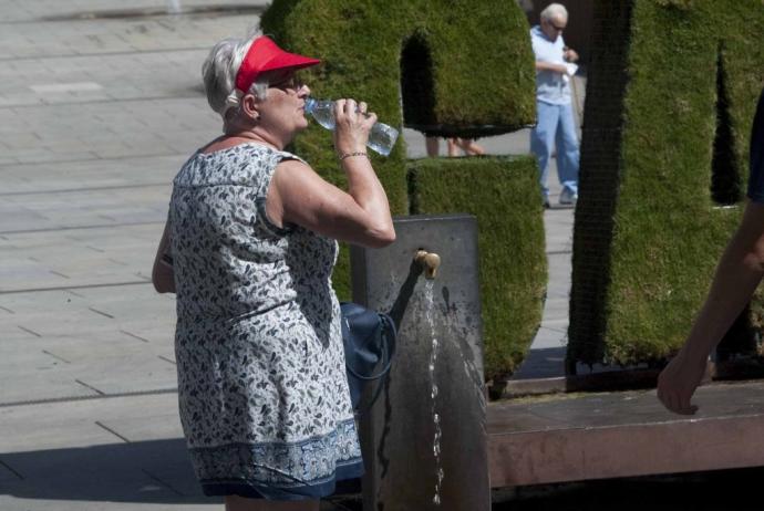 Una mujer se refresca en las fuentes de agua de Vitoria.