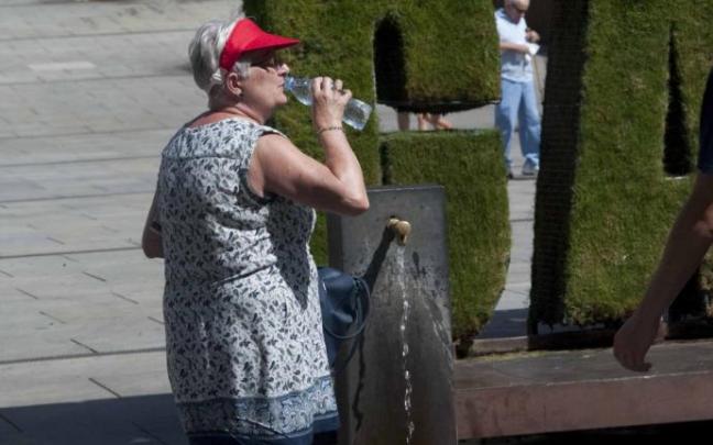 Una mujer se refresca en las fuentes de agua de Vitoria. Una mujer se refresca en las fuentes de agua de Vitoria.