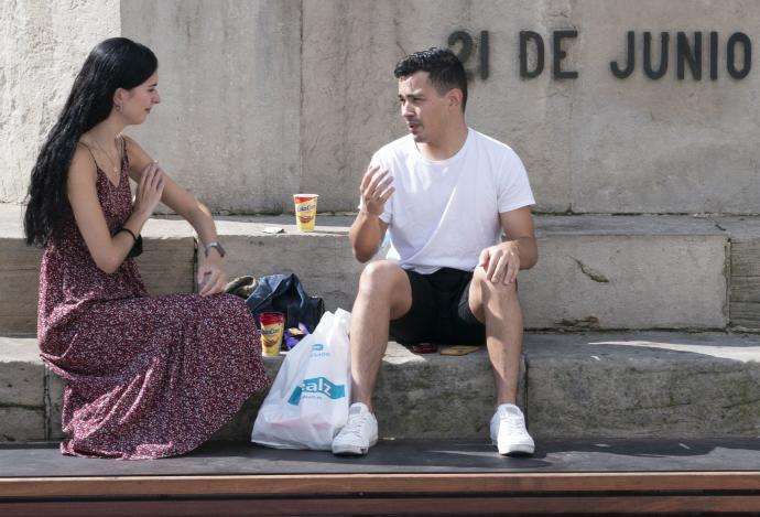 Dos jóvenes charlan sentados en el monumento a la Batalla de Vitoria.