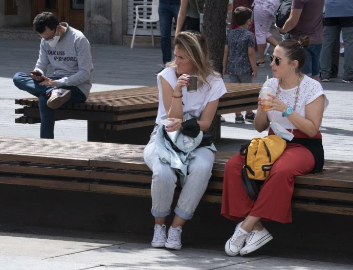 Dos jóvenes descansan en un banco del centro de Vitoria.