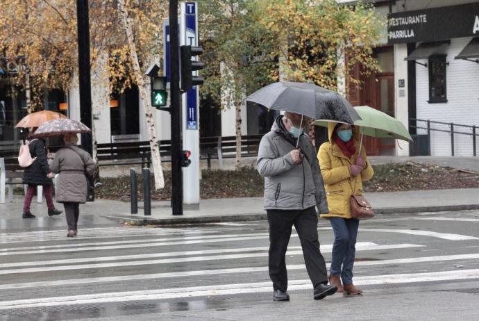 Varias personas pasean por Vitoria durante las recientes lluvias.