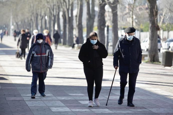 Varias personas pasean por Vitoria protegidas con sus mascarillas.