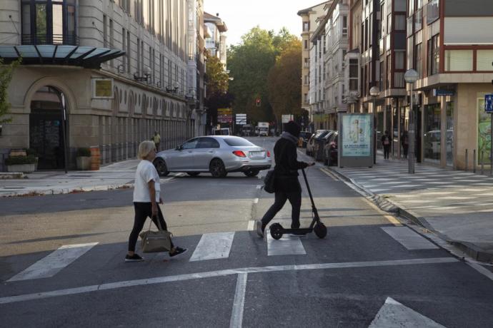 Personas cruzando un paso de peatones en Vitoria, una de ellas con un patinete
