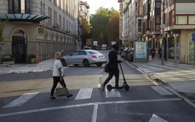Personas cruzando un paso de peatones en Vitoria, una de ellas con un patinete