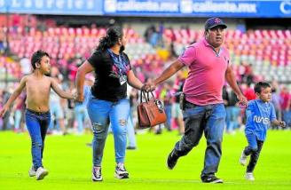 Una familia huye de los disturbios durante el Querétano-Atlas. Foto: Efe