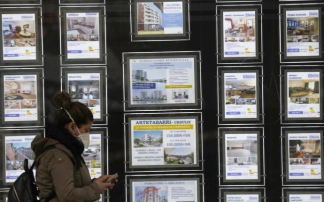 Una joven pasa delante del escaparate de una inmobiliaria. Una joven pasa delante del escaparate de una inmobiliaria.