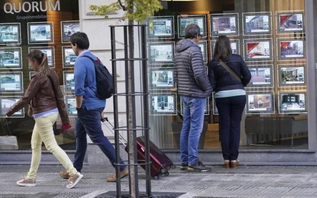 Dos personas miran el escaparate de una inmobiliaria.