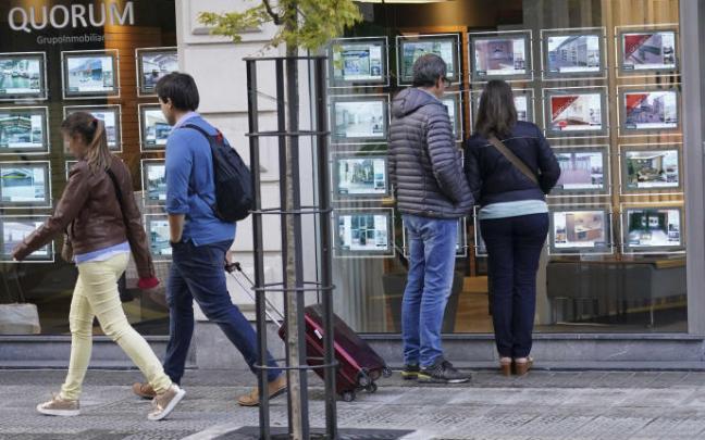 Dos jóvenes observan el escaparate de una inmobiliaria.