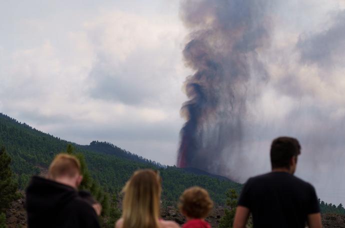 Varias personas observan la actividad de la erupción volcánica.