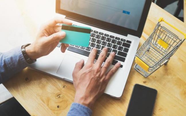 Un hombre revisa su tarjeta durante una compra por internet. Un hombre revisa su tarjeta durante una compra por internet.