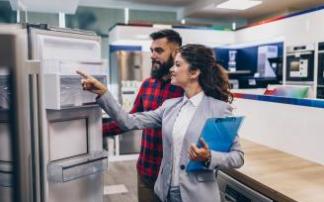 Una vendedora enseña un frigorífico a un cliente en una tienda de electrodomésticos.