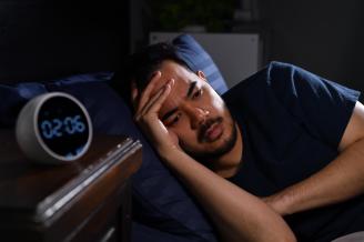 Un hombre, desvelado en la cama de madrugada.