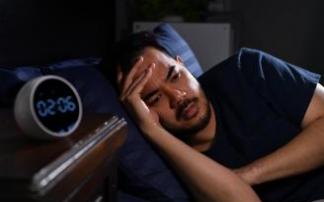 Un hombre, desvelado en la cama de madrugada.