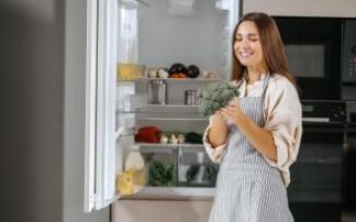 Una mujer guarda verdura en su frigorífico.