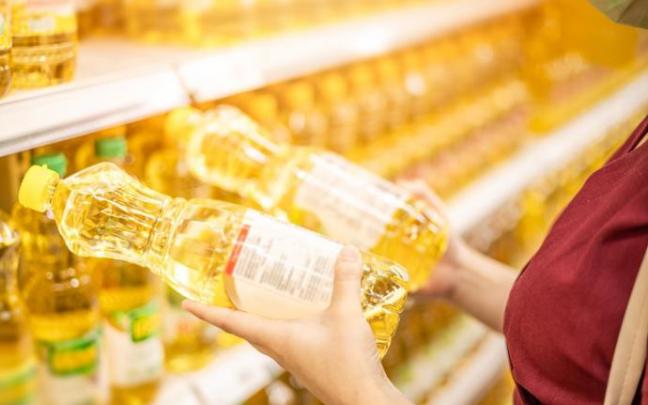 Una mujer coge dos botellas de aceite de girasol en un supermercado. Una mujer coge dos botellas de aceite de girasol en un supermercado.