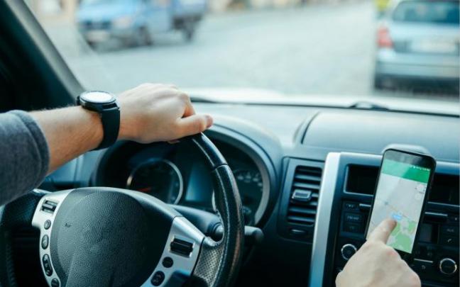 Manipulación de un móvil en un soporte en el salpicadero de un coche.