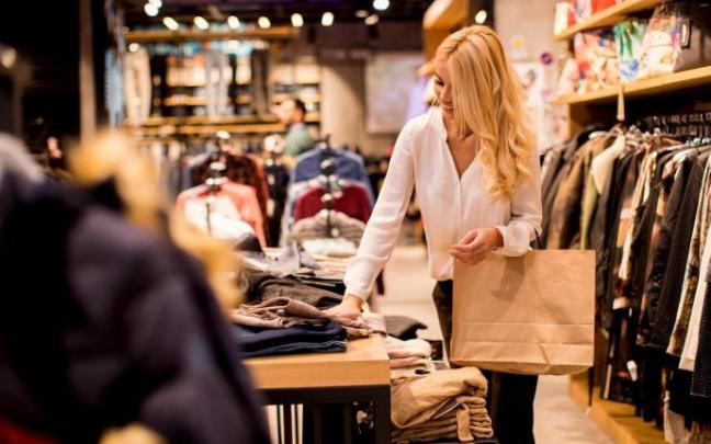 Una mujer mira pantalones en una tienda de ropa. Una mujer mira pantalones en una tienda de ropa.