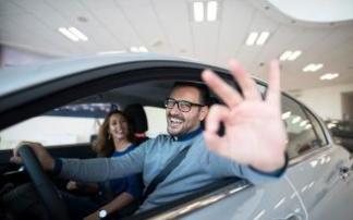 Una mujer y un hombre salen de un concesionario con su nuevo coche. Una mujer y un hombre salen de un concesionario con su nuevo coche.