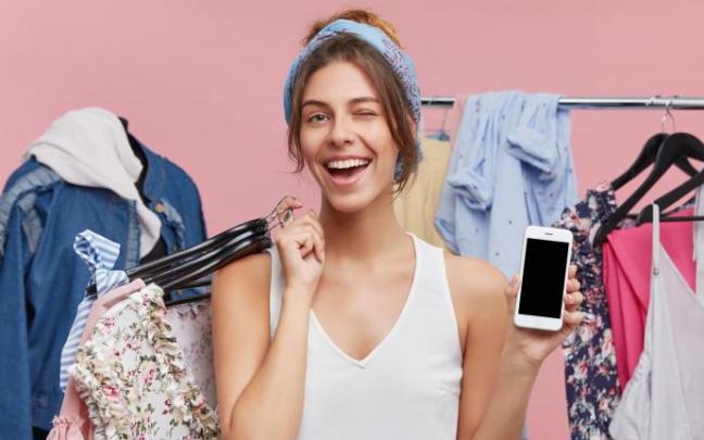 Una joven rodeada de prendas de ropa.