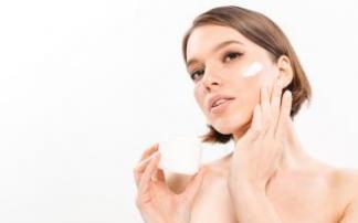 Una mujer se aplica una crema en el rostro. Una mujer se aplica una crema en el rostro.
