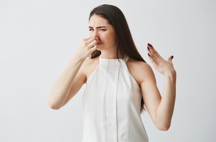 Una joven, tapándose la nariz ante un olor desagradable.