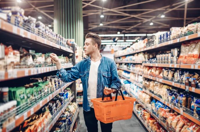 Un hombre revisa varios productos de las estanterías de un supermercado.