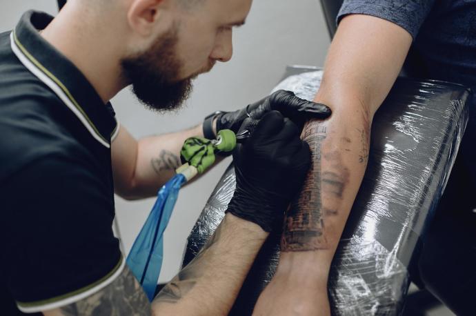 Un tatuador realiza un tatuaje en el brazo de un hombre.