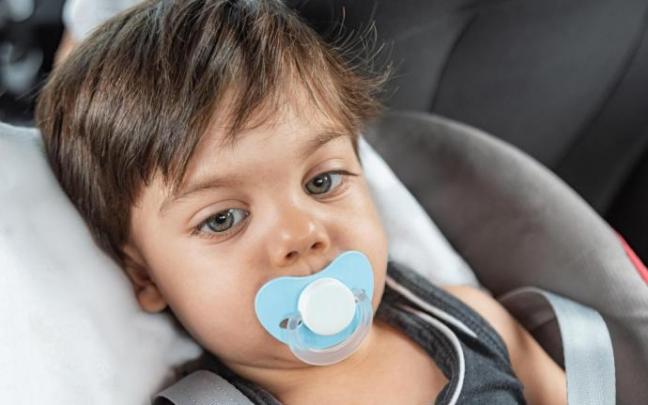 Un bebé con chupete en una sillita de coche. Un bebé con chupete en una sillita de coche.