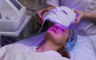 Una mujer durante un tratamiento con una máscara de luz LED. Una mujer durante un tratamiento con una máscara de luz LED.